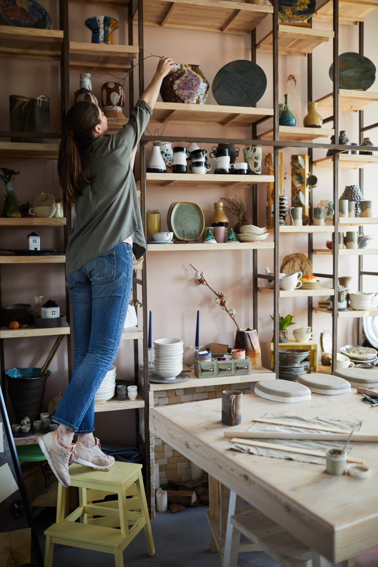 Person arranging items on wooden shelves in a workshop setting