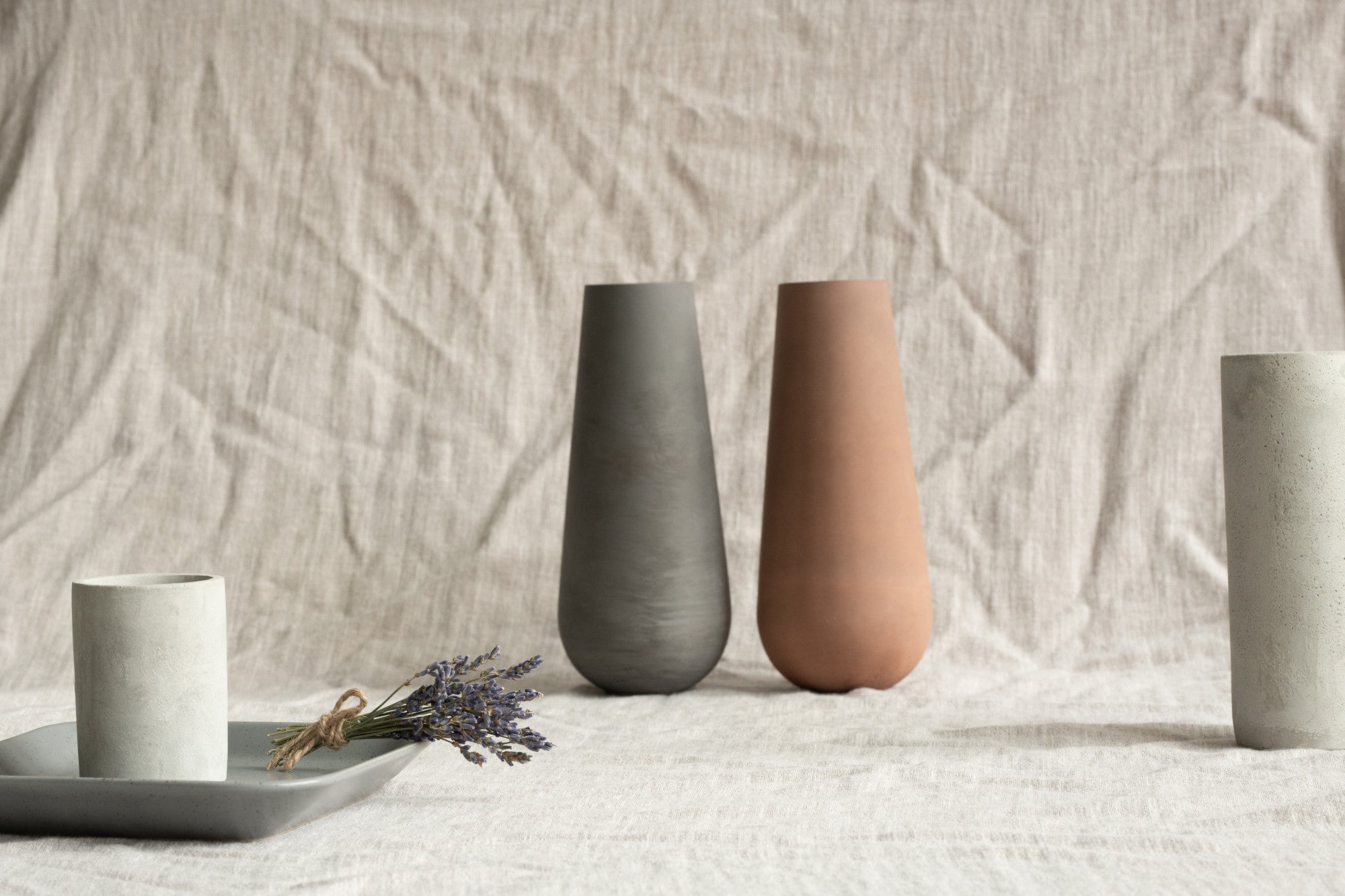 Three ceramic vases in different colors on a textured surface with a neutral background